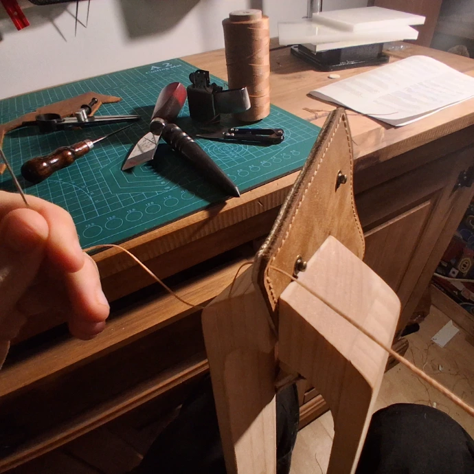 Image of handmade trifold leather wallet in process of being stitched by hand