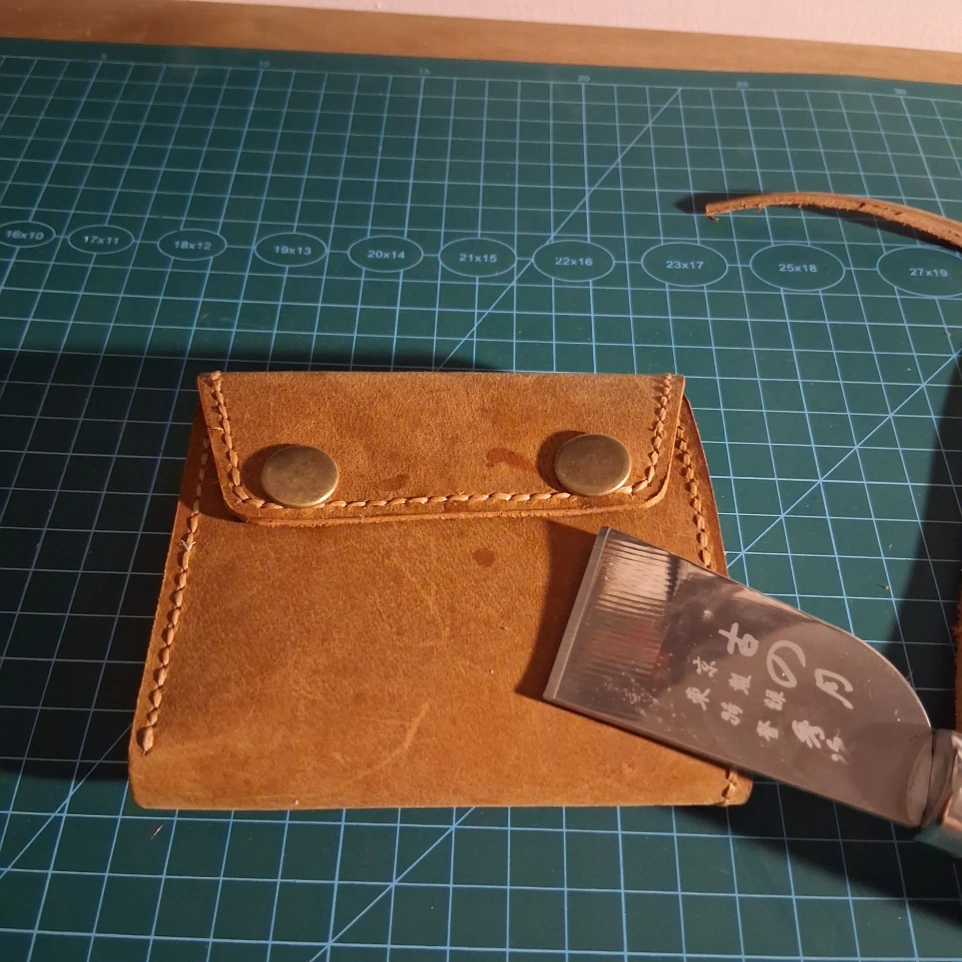 Closed image of handmade trifold leather wallet next to thread